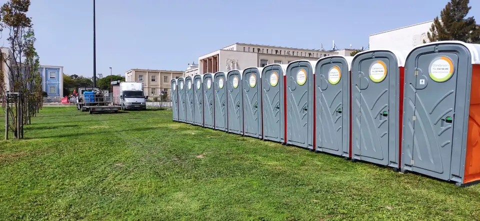 Fila longa de cabines sanitárias INOVSAN instaladas num relvado para um evento